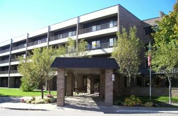 a building with a black roof and trees in front of it